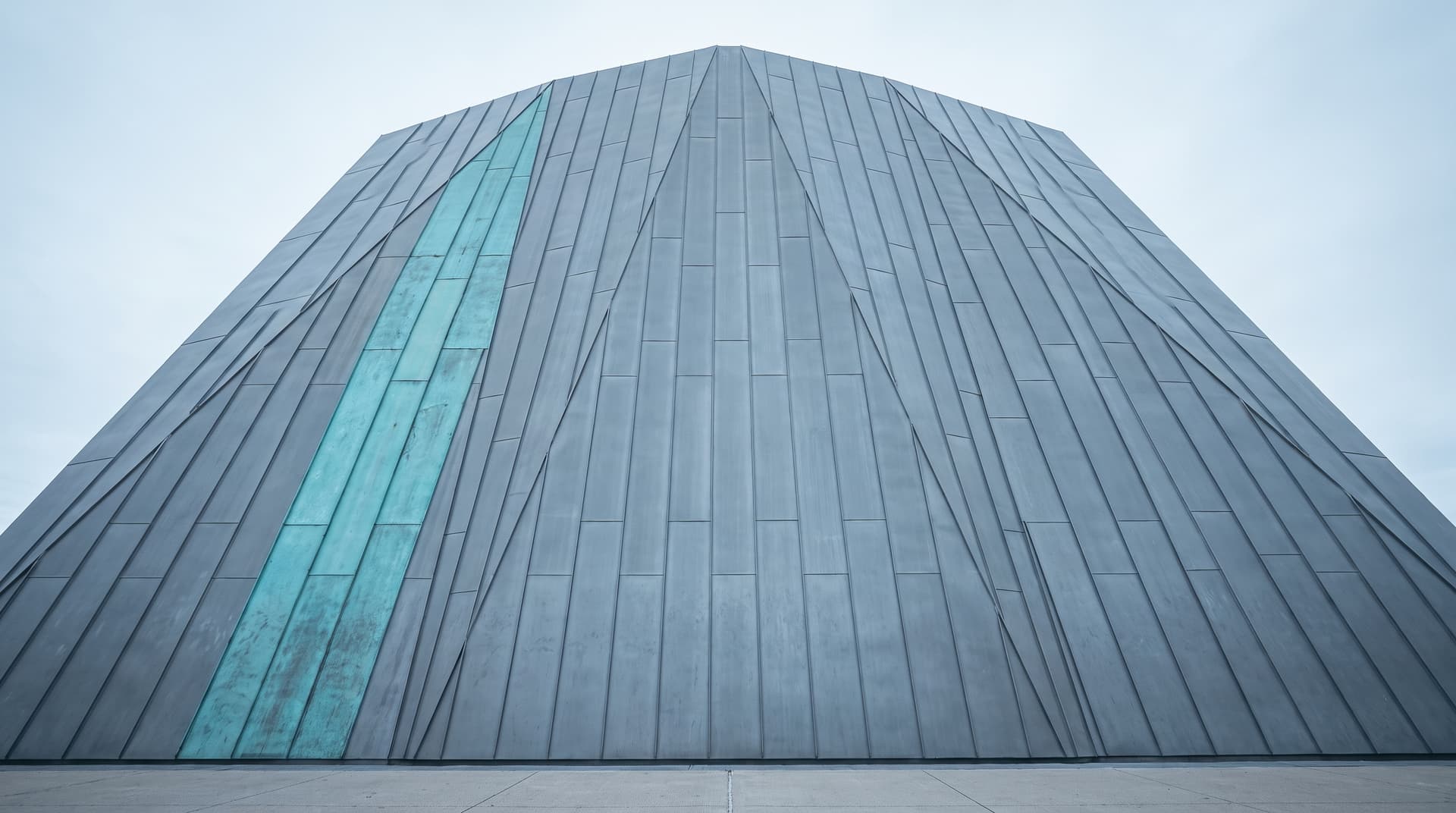 Museo con facciata in zinco piegato fotografato dal basso, una fascia di pannelli su misura in rame patinato verde