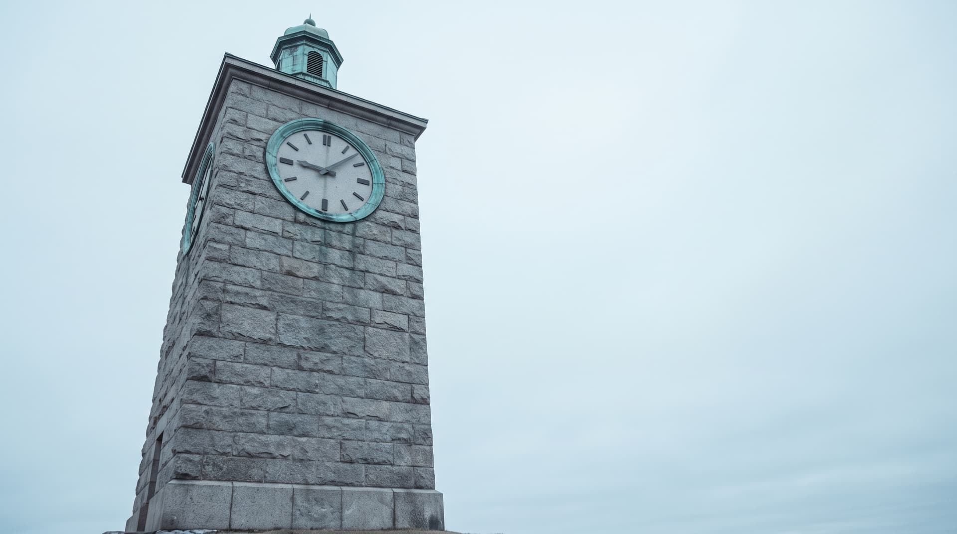 Stone clock tower with a verdigris copper clock face and lantern cupola under an overcast sky – a metaphor for AI assistants that keep track of appointments and tasks