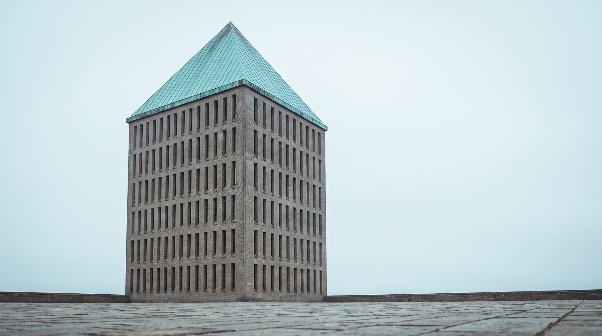 Archive tower with narrow slit windows and a verdigris copper roof under an overcast sky – a visual metaphor for searchable company knowledge