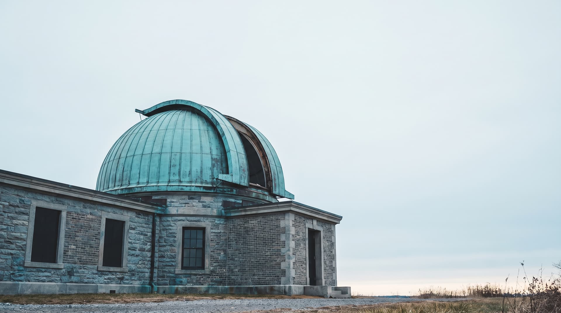 Sternwarte mit patinierter Kupferkuppel unter bedecktem Himmel, von unten fotografiert